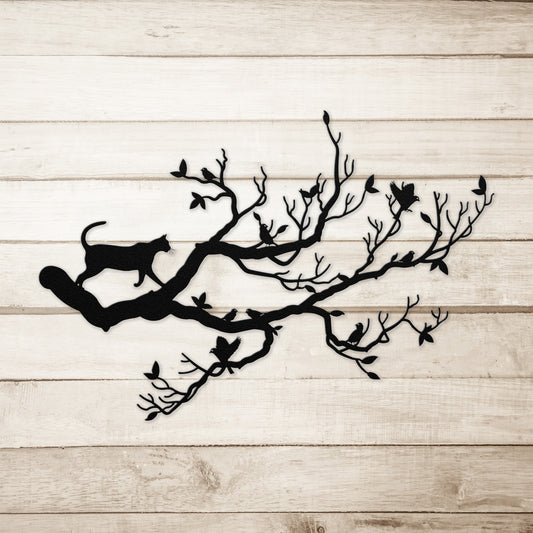 A black metal wall art decor of a cat stalking birds on a branch on a simple wood background.