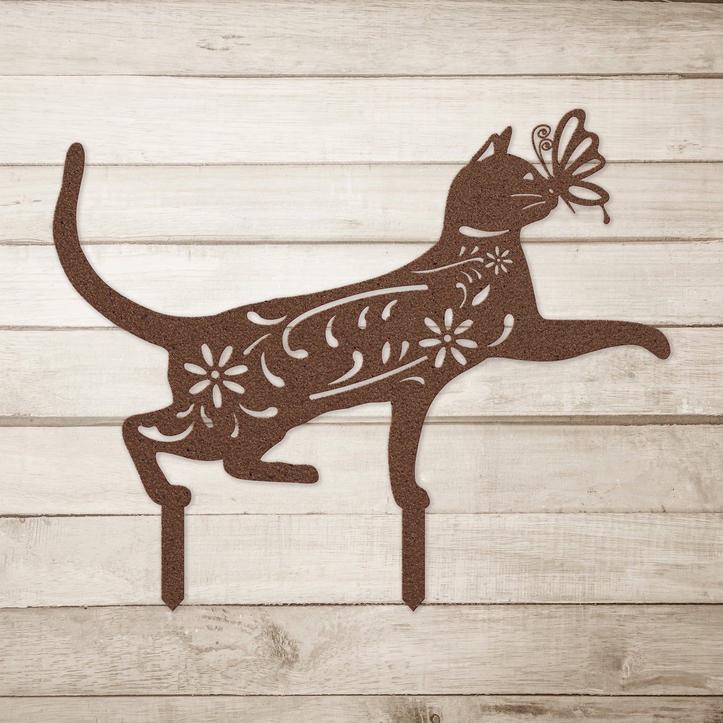 A copper yard/garden stake of a cat with a butterfly on it nose and floral elements on it body.