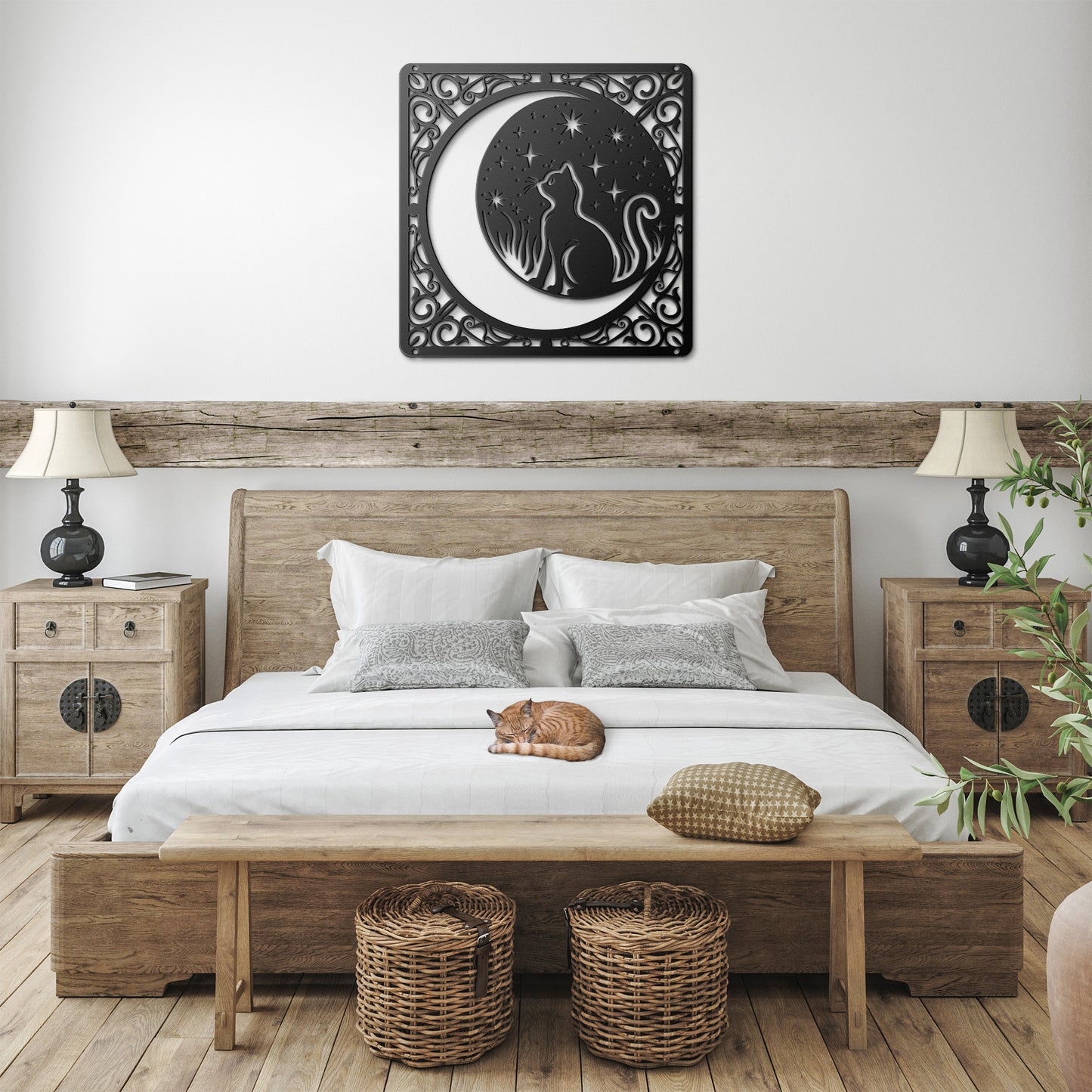 A black home decor metal sign of a cat inside a crescent moon next to a field of stars. All of this is bordered by floral vines. It hangs in a farmhouse bedroom above an orange tabby cat.