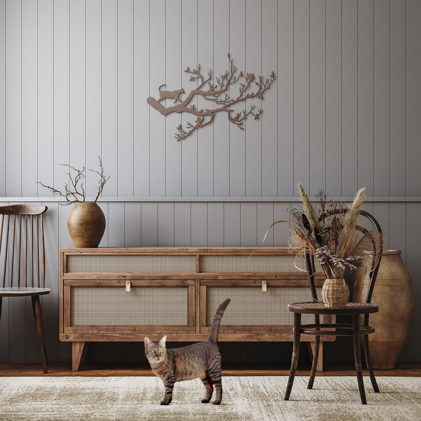 A copper metal wall art decor of a cat stalking birds on a branch hanging in a rustic hallway.