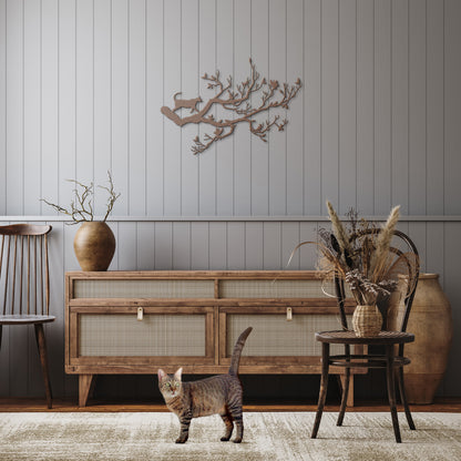 A copper metal wall art decor of a cat stalking birds on a branch hanging in a rustic hallway.