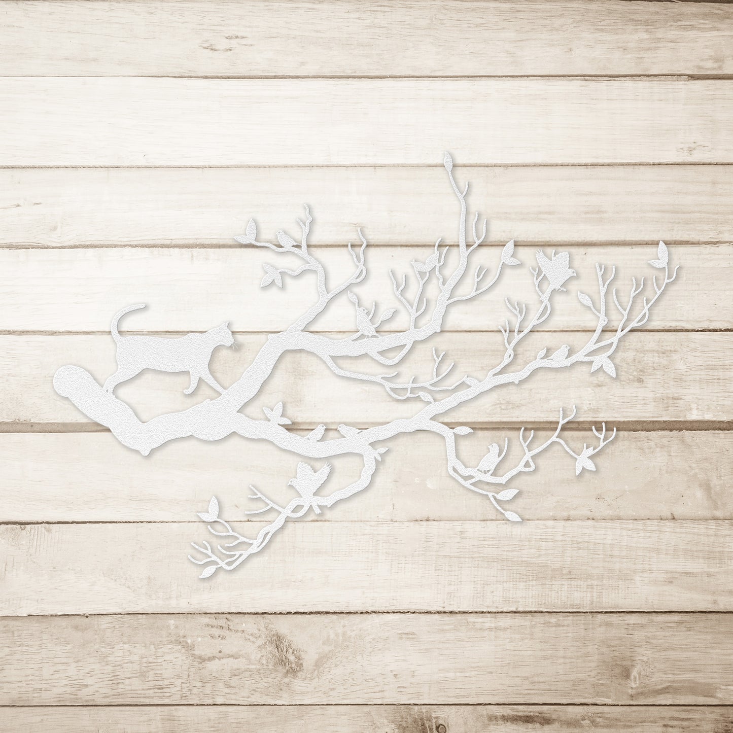 A white metal wall art decor of a cat stalking birds on a branch on a simple wood background.