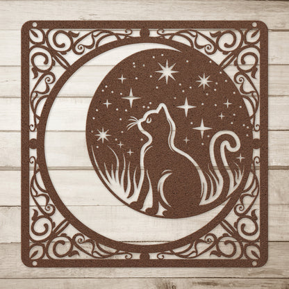 A copper home decor metal sign of a cat inside a crescent moon next to a field of stars. All of this is bordered by floral vines. Simple wood background.