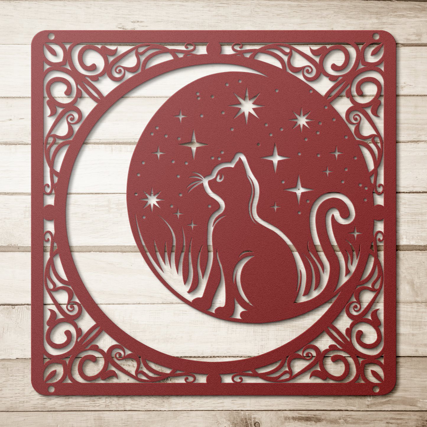 A red home decor metal sign of a cat inside a crescent moon next to a field of stars. All of this is bordered by floral vines.  Simple wood background.