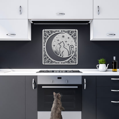 A copper home decor metal sign of a cat inside a crescent moon next to a field of stars. All of this is bordered by floral vines. It hangs in a dark kitchen above a grey cat.