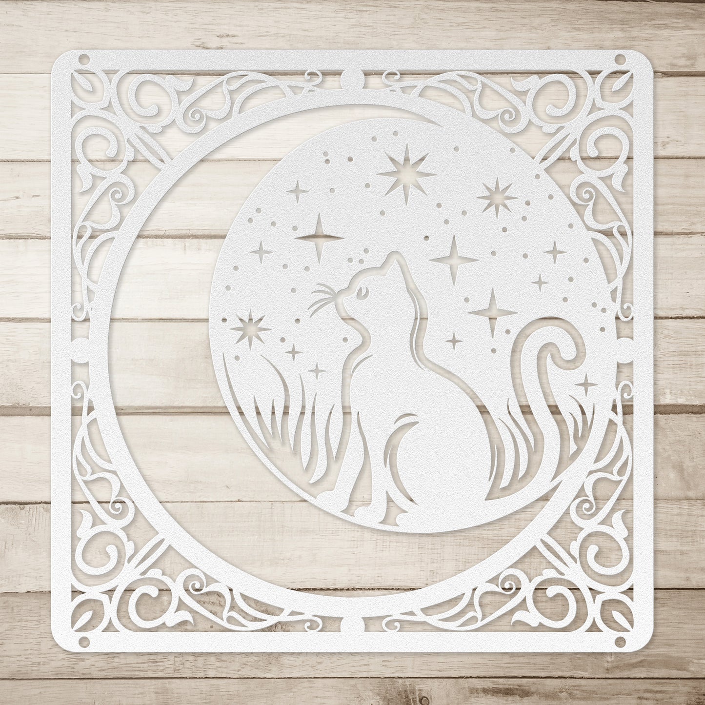 A silver home decor metal sign of a cat inside a crescent moon next to a field of stars. All of this is bordered by floral vines. Simple wood background.